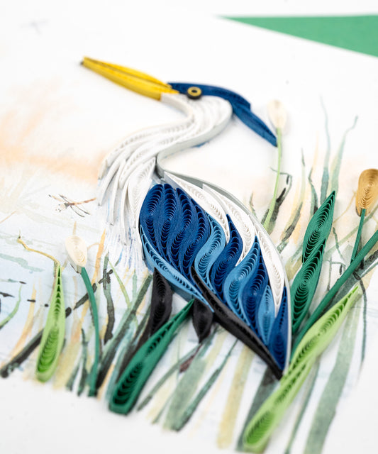 Close up of Greeting Card with a Great Blue Heron sits upon a rock along a stream surrounded lilypads and cattails.