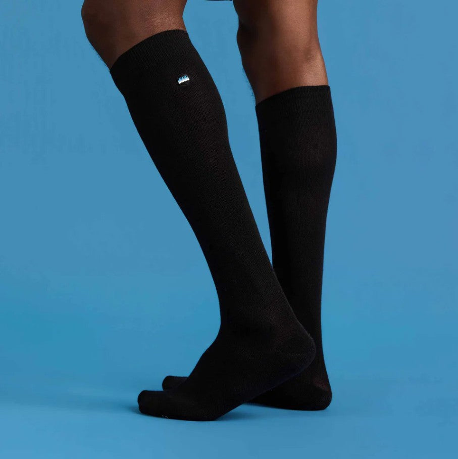 Black knee-high socks worn by a person on a blue background