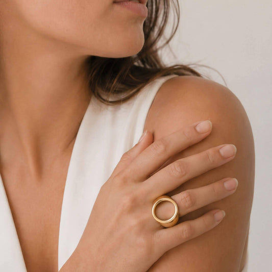 Woman wearing a gold ring on her hand with a neutral background