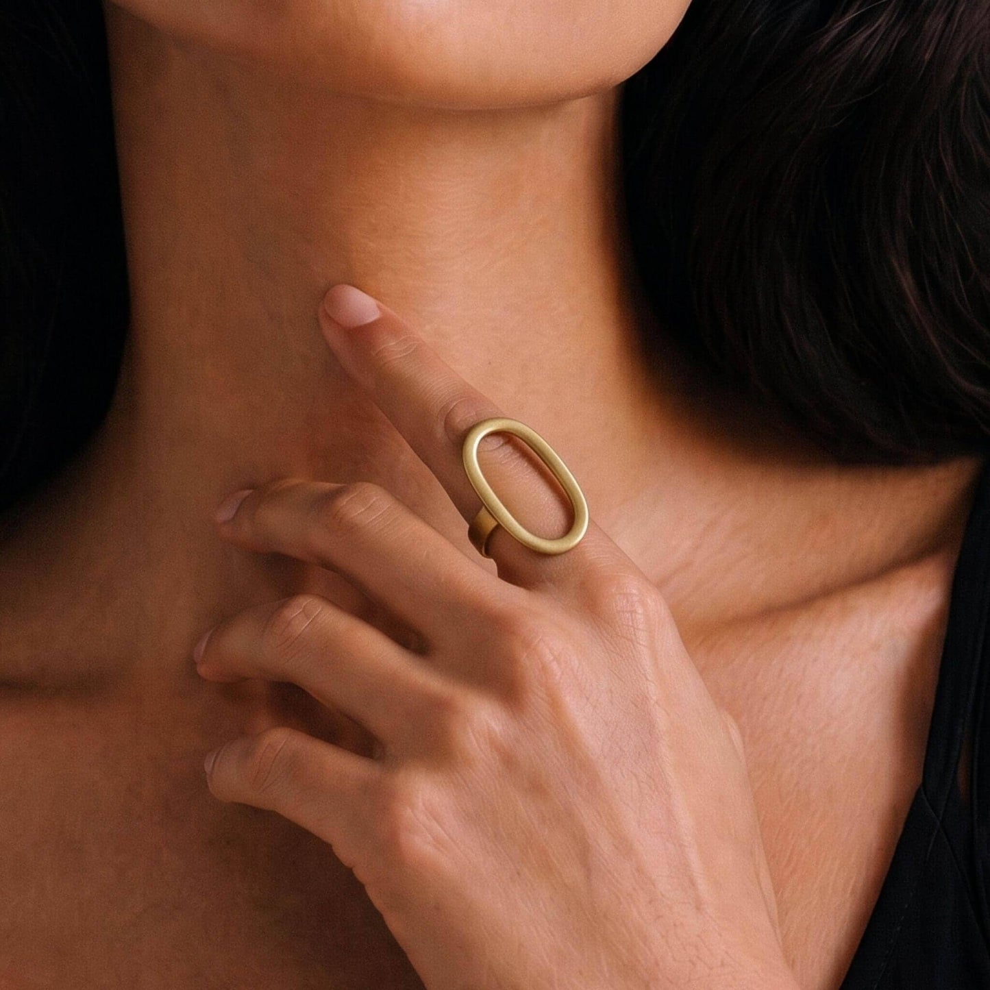 Close-up of a hand wearing a gold ring on a dark background