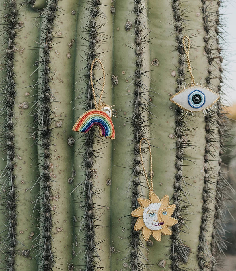 Close-up of a handcrafted sun and moon ornament showing intricate embroidery and colorful beaded details.