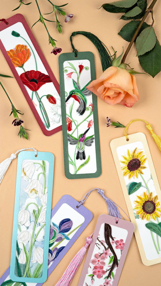 Six bookmarks in various colors and quilled patterns are arranged on a peach background and shown surrounded with flowers.