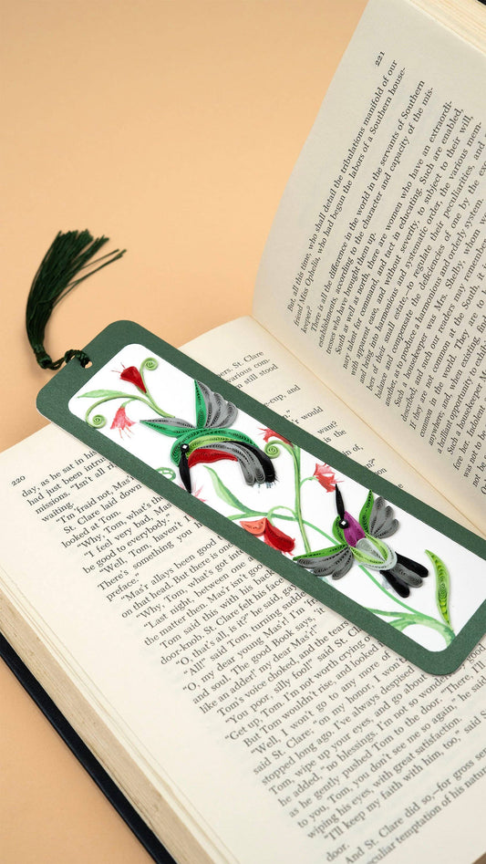 Green hummingbird bookmark rests on an open book.