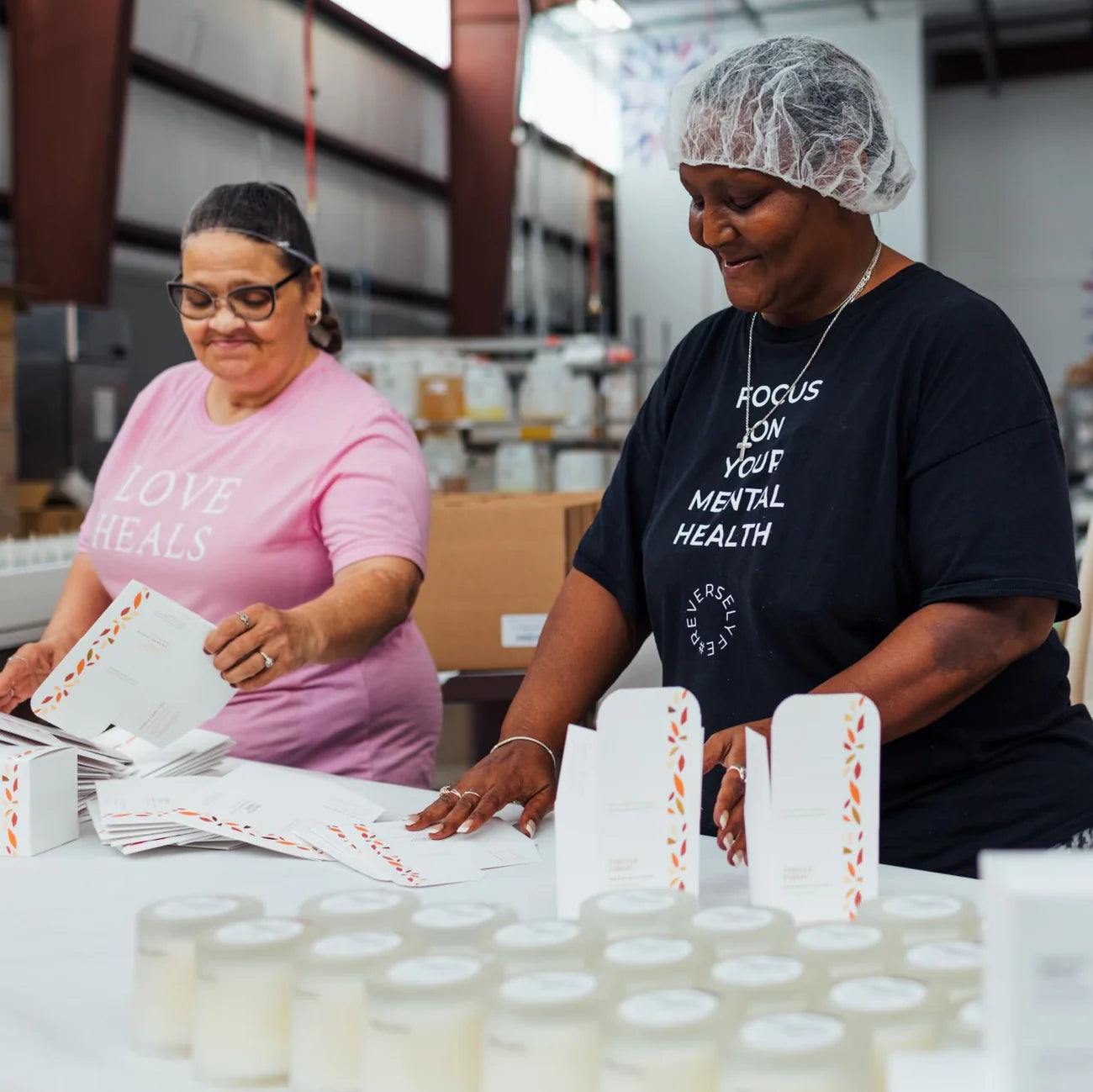 Two women working in a warehouse setting with packaging materials.