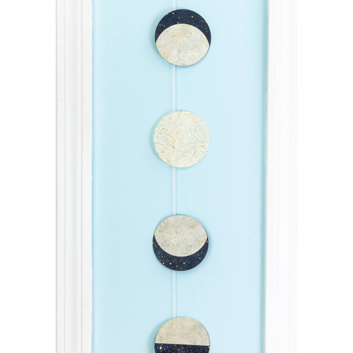 Decorative hanging with moon phases on a light blue background