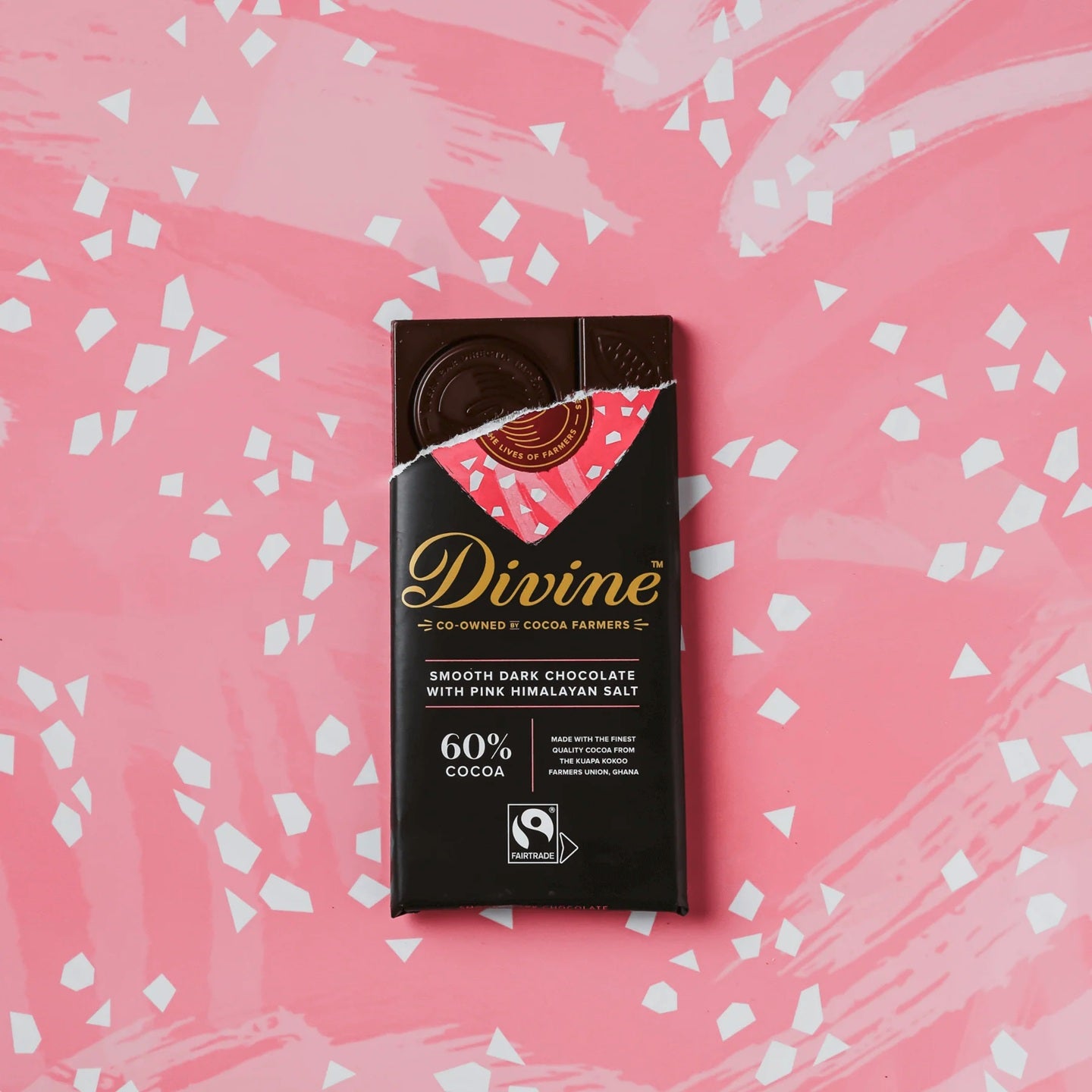 Divine chocolate bar packaging on a pink background with white abstract patterns that look like sea salt