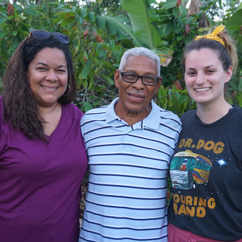 Three people posing together in front of green foliage