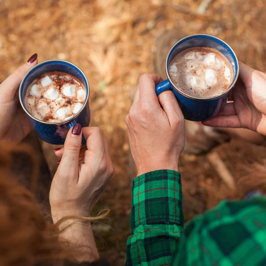 Two people holding blue mugs with hot chocolate and marshmallows