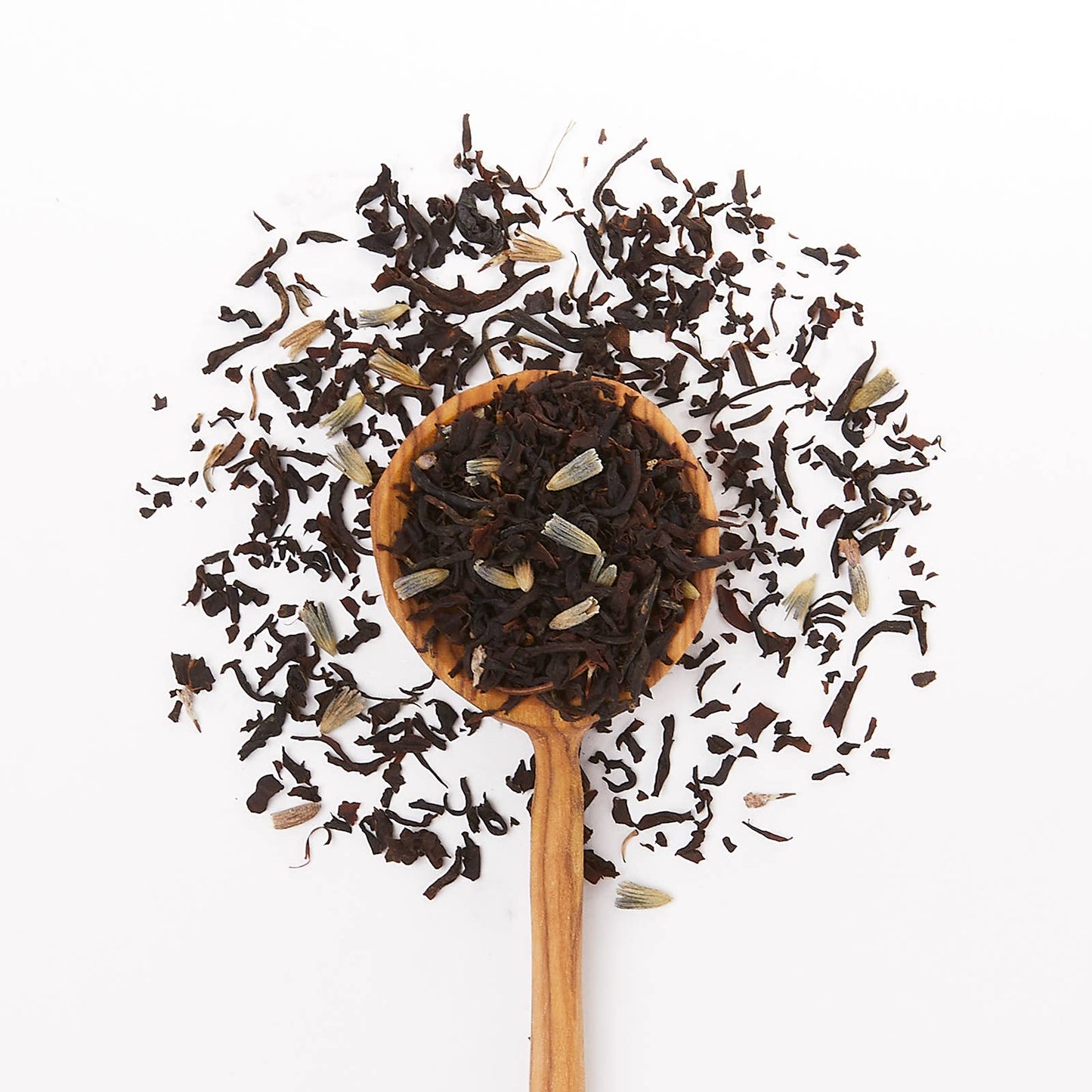 Wooden spoon filled with black tea leaves on a white background