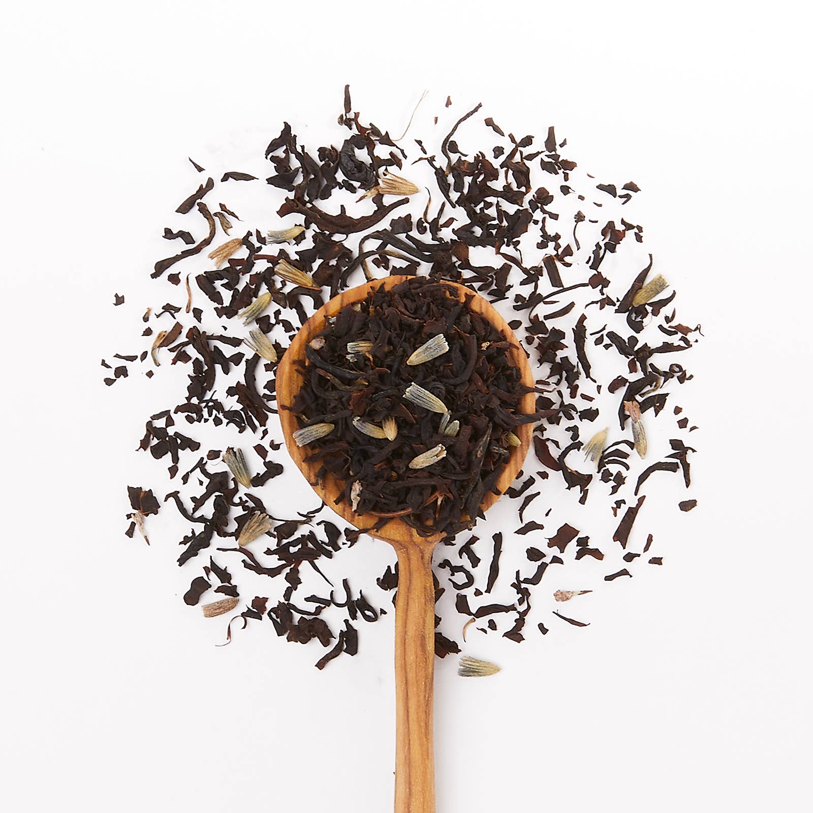 Wooden spoon filled with black tea leaves on a white background