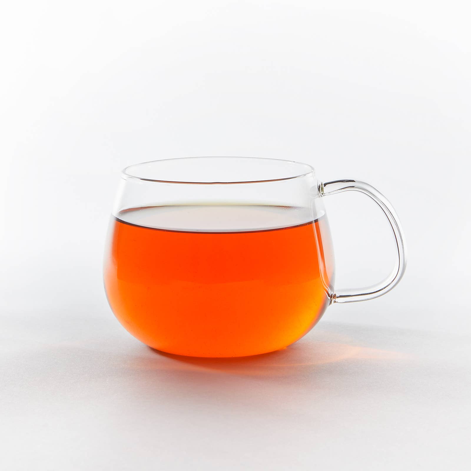 Clear glass mug filled with orange liquid on a white background