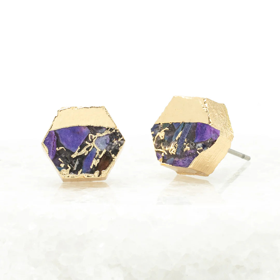 Hexagonal gold and purple earrings on a white surface