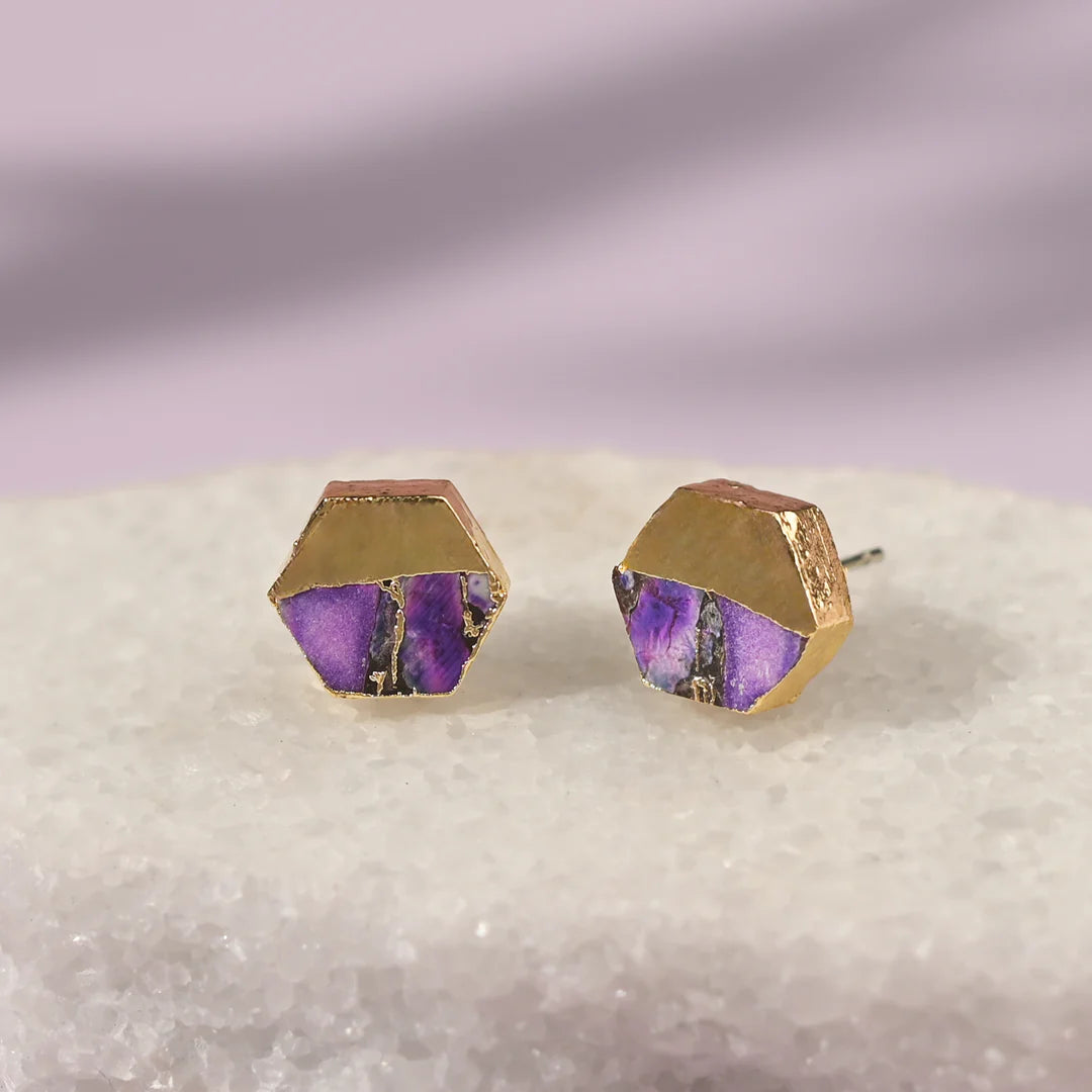 Hexagonal gold and purple earrings set on a neutral background.