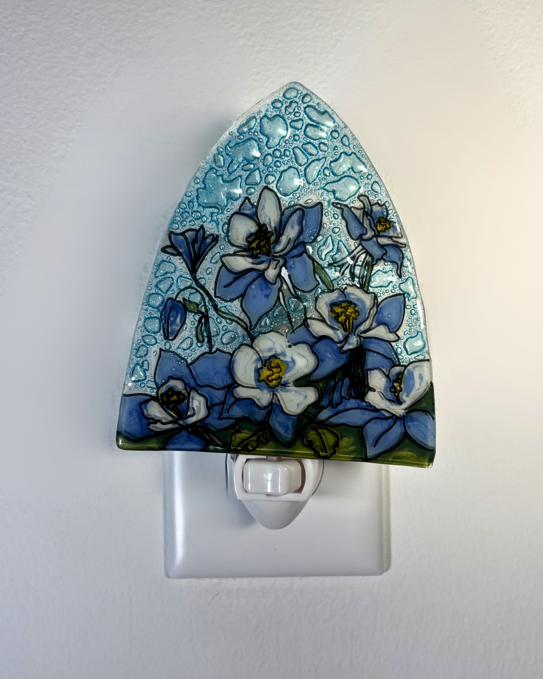 Decorative night light with blue floral design on a white wall