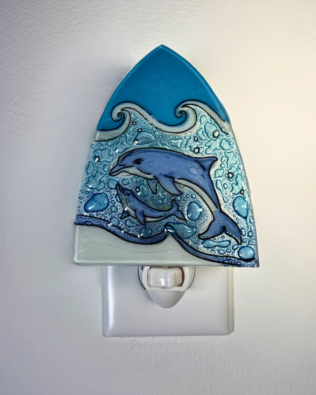Decorative night light with dolphins and wave design on a white background