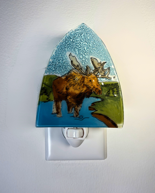 Glass night light with a moose design on a white wall