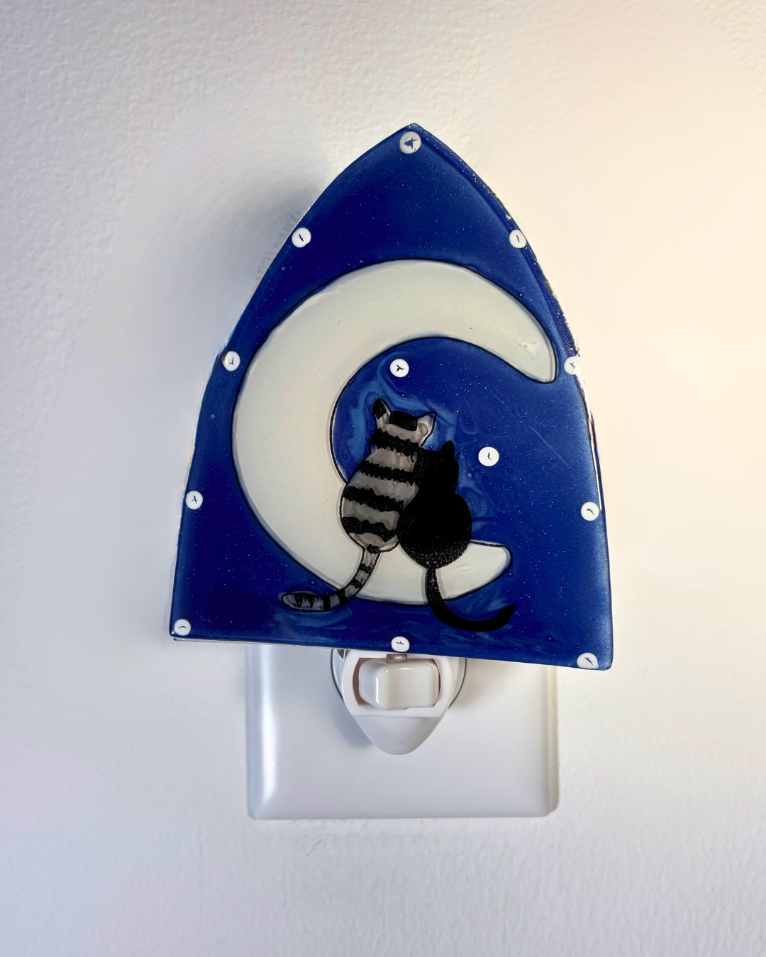 Night light with a two cats sitting on a white crescent moon against a starry blue background