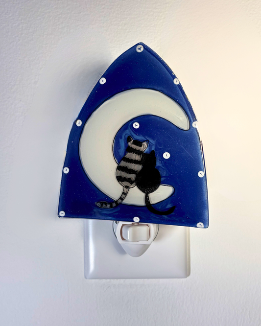Night light with a two cats sitting on a white crescent moon against a starry blue background