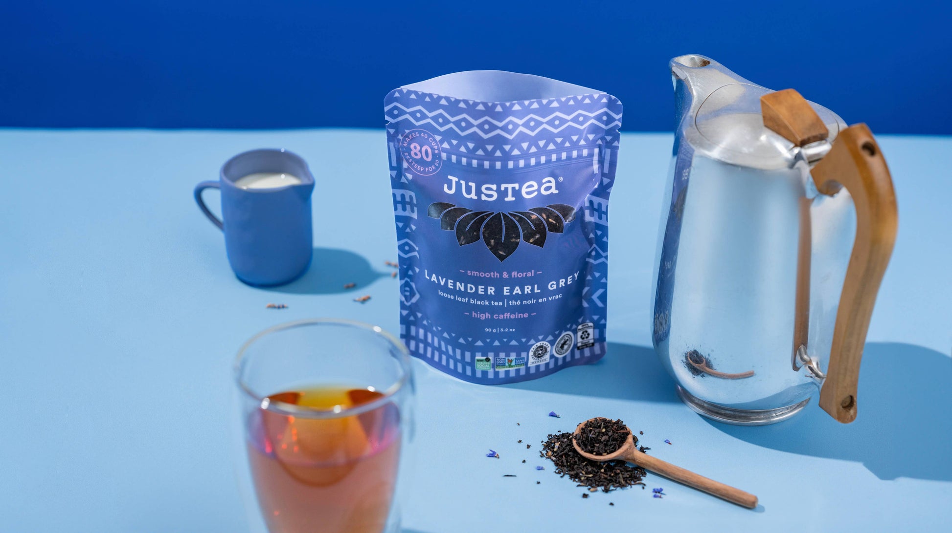 Justea lavender earl grey tea packaging with a glass of tea and teapot on a blue background