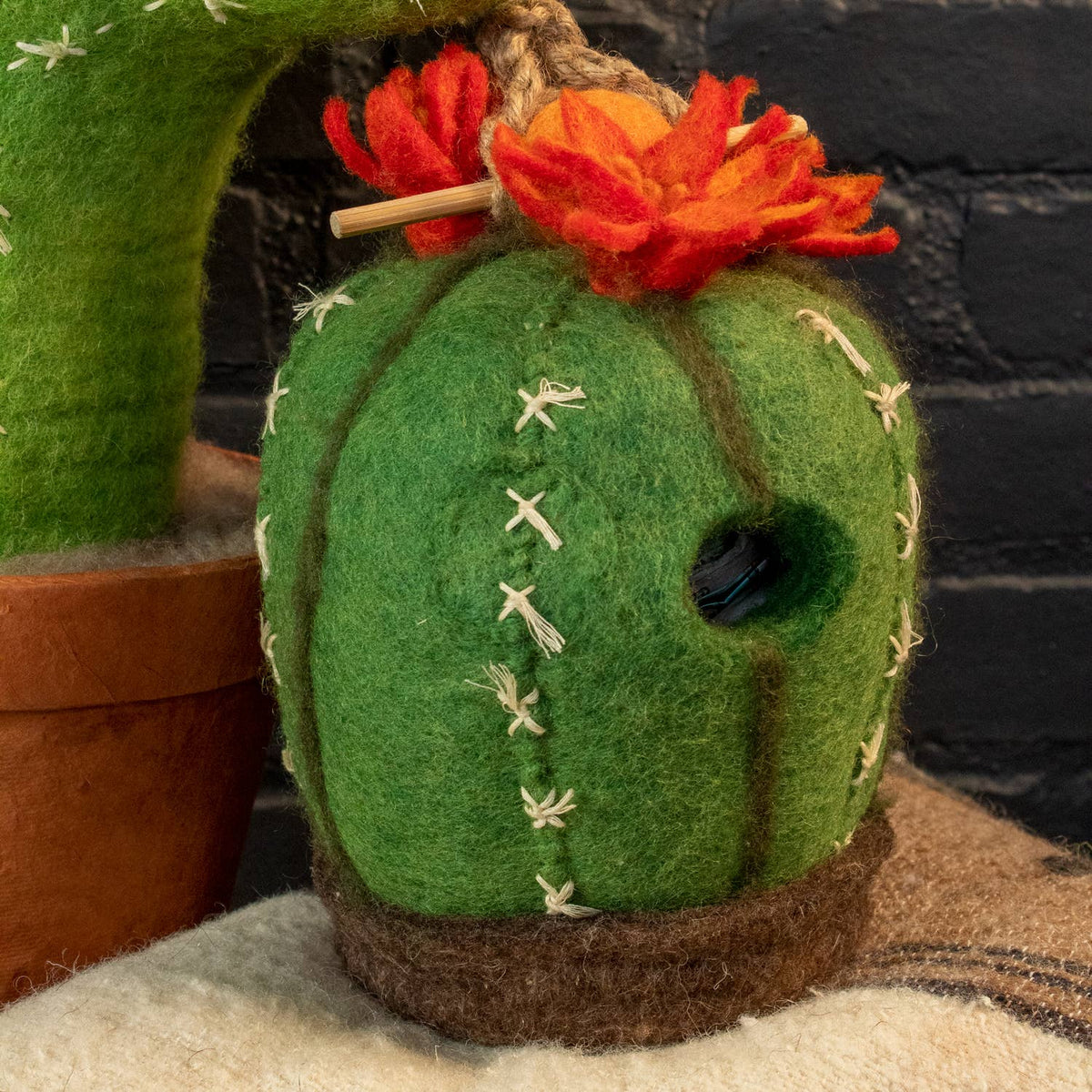 Felt cactus with orange flowers on a textured surface
