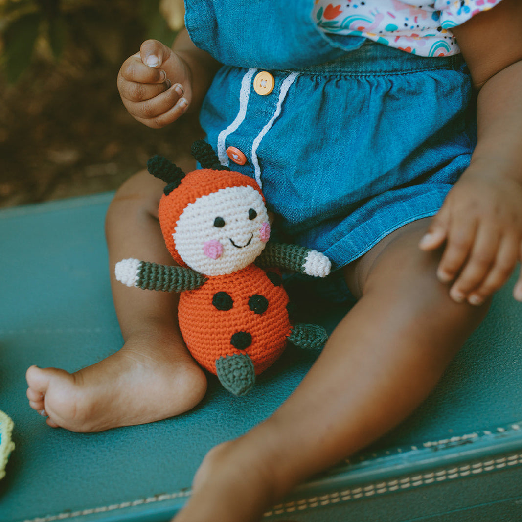 Child playing with crochet toys on a suitcase