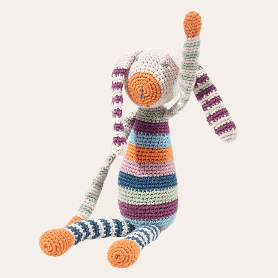 Colorful striped crochet rabbit toy on a white background