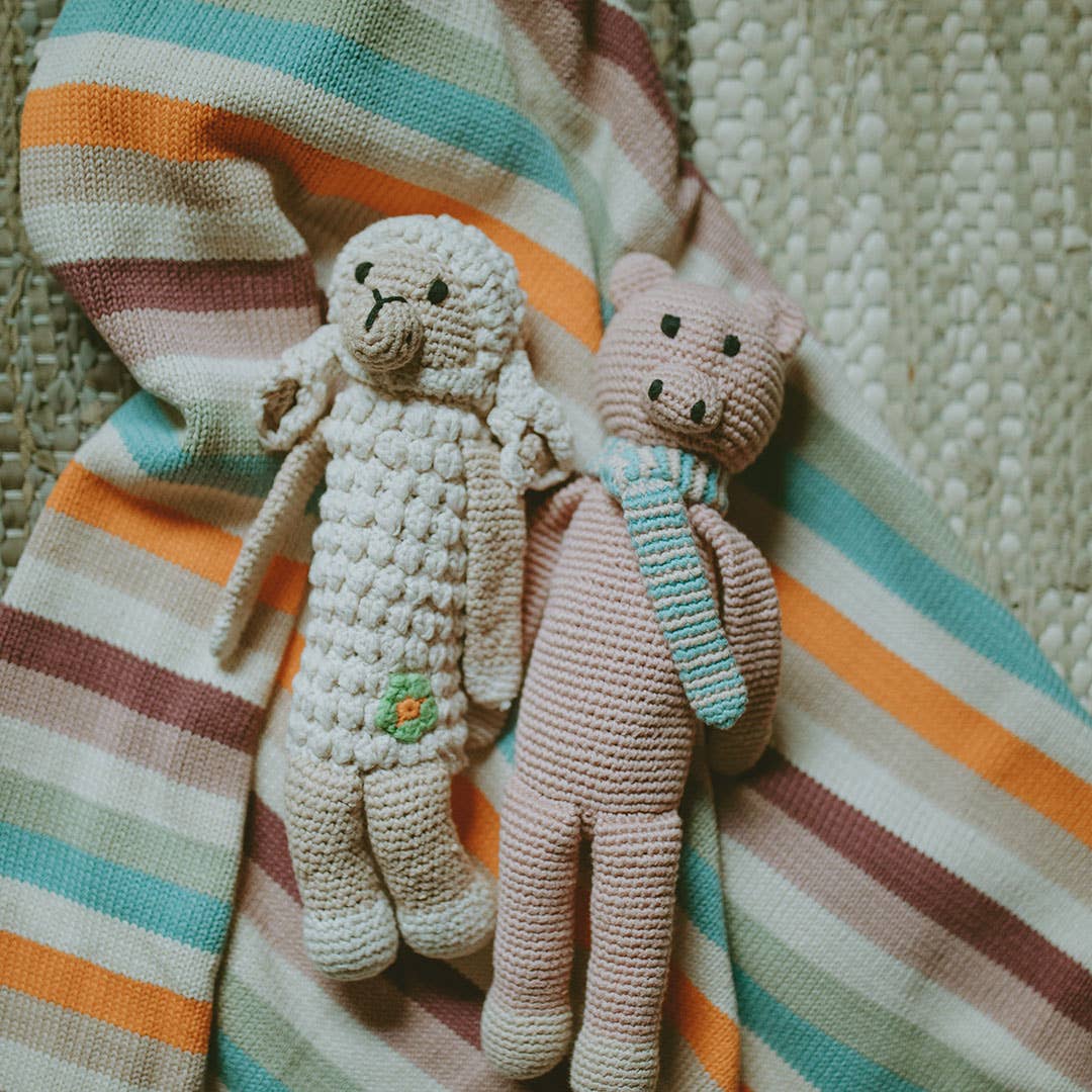 Two crocheted stuffed animals on a striped fabric background