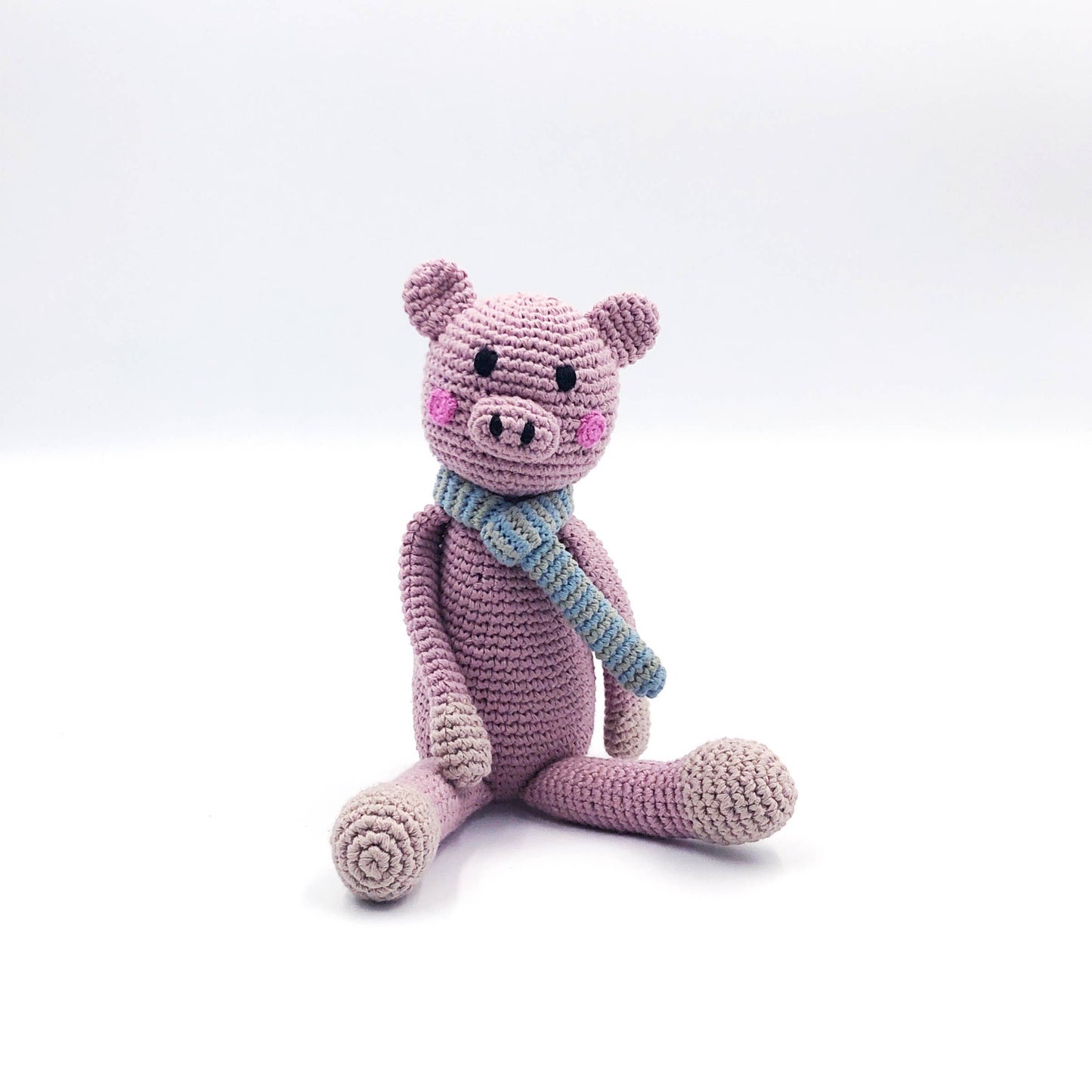 Crocheted pink pig toy with a blue scarf on a white background