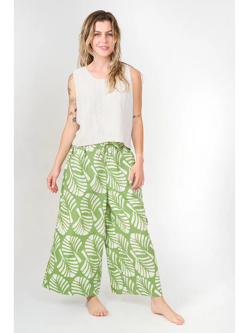 Woman wearing green patterned pants and a white top on a white background
