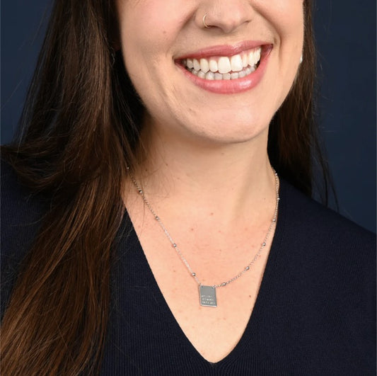 Woman wearing a necklace with a pendant against a dark background