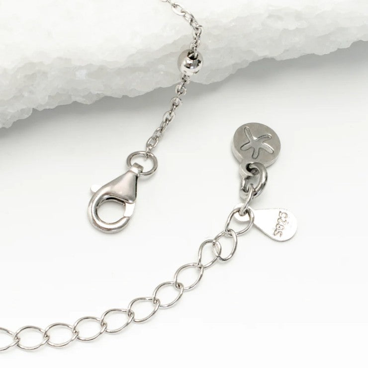Close-up of a silver bracelet with clasp and heart-shaped tag on a white background