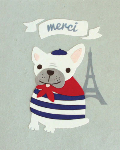 A greeting card featuring a cartoon illustration of a bulldog wearing a striped scarf with a red bow, in front of a grey background with a 'merci' text and a silhouette of the Eiffel Tower.