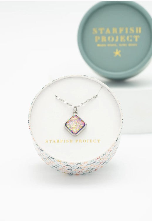 Square artifical opal stone in a Starfish Project box on a white background
