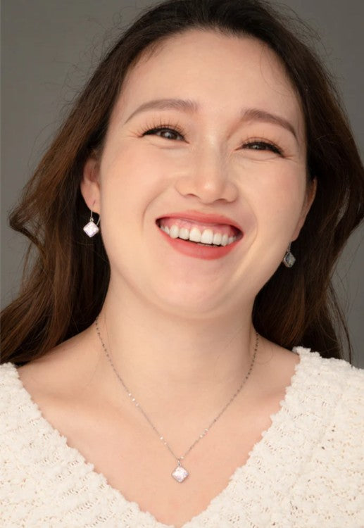Woman wearing a matching necklace and earring set on a white background.