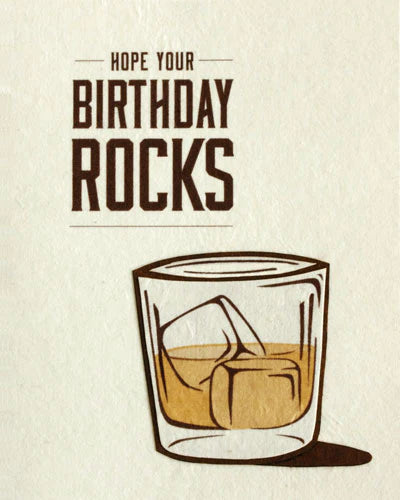 Birthday card with a glass of whiskey and ice cubes on a beige background.