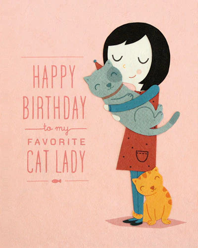A greeting card with an illustration of a person hugging a gray cat, with a smaller orange cat standing beside them. The text on the card reads 'Happy Birthday to my favorite Cat Lady.