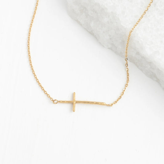 Gold necklace with a sideways cross pendant on a white background