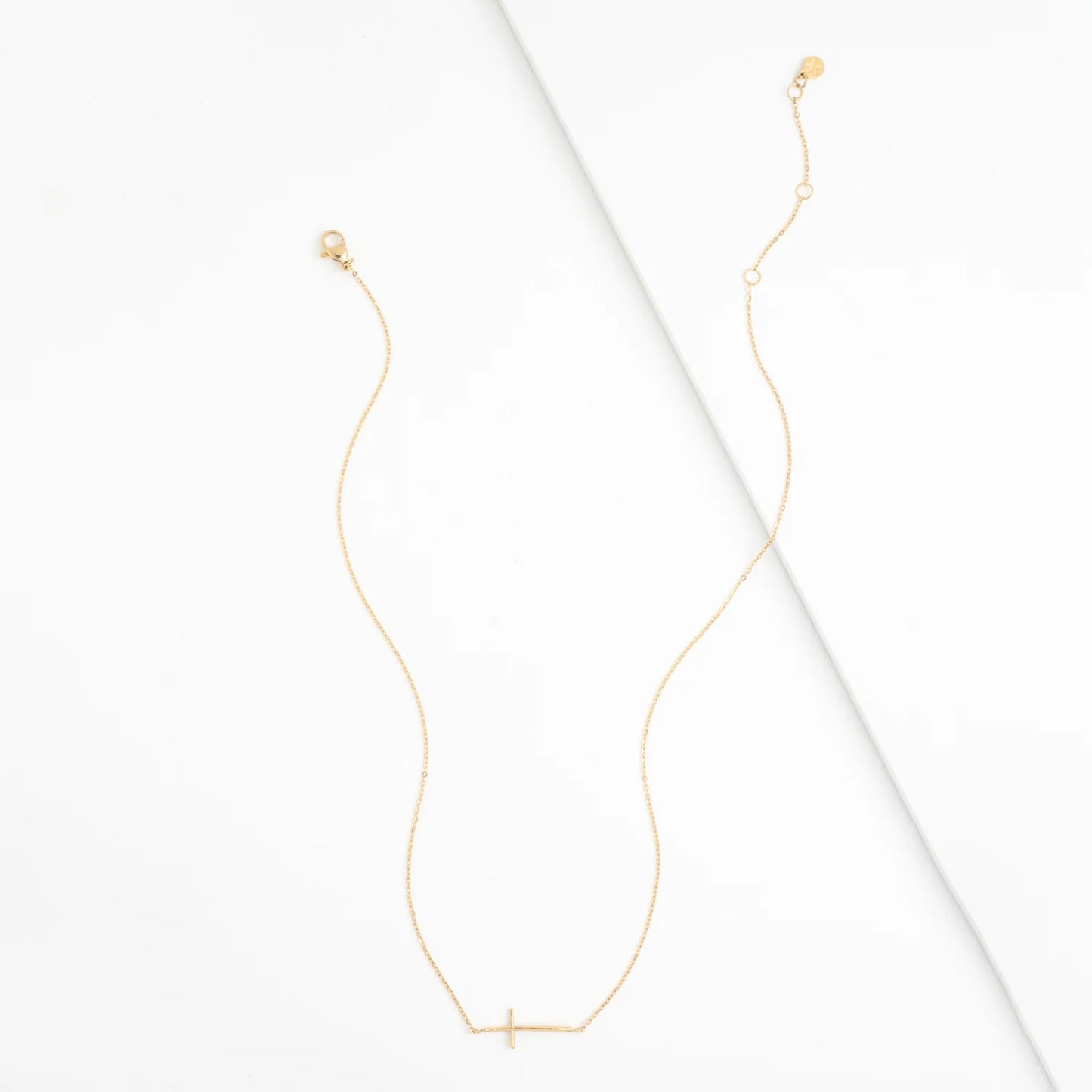 Gold necklace with a small cross pendant on a white background