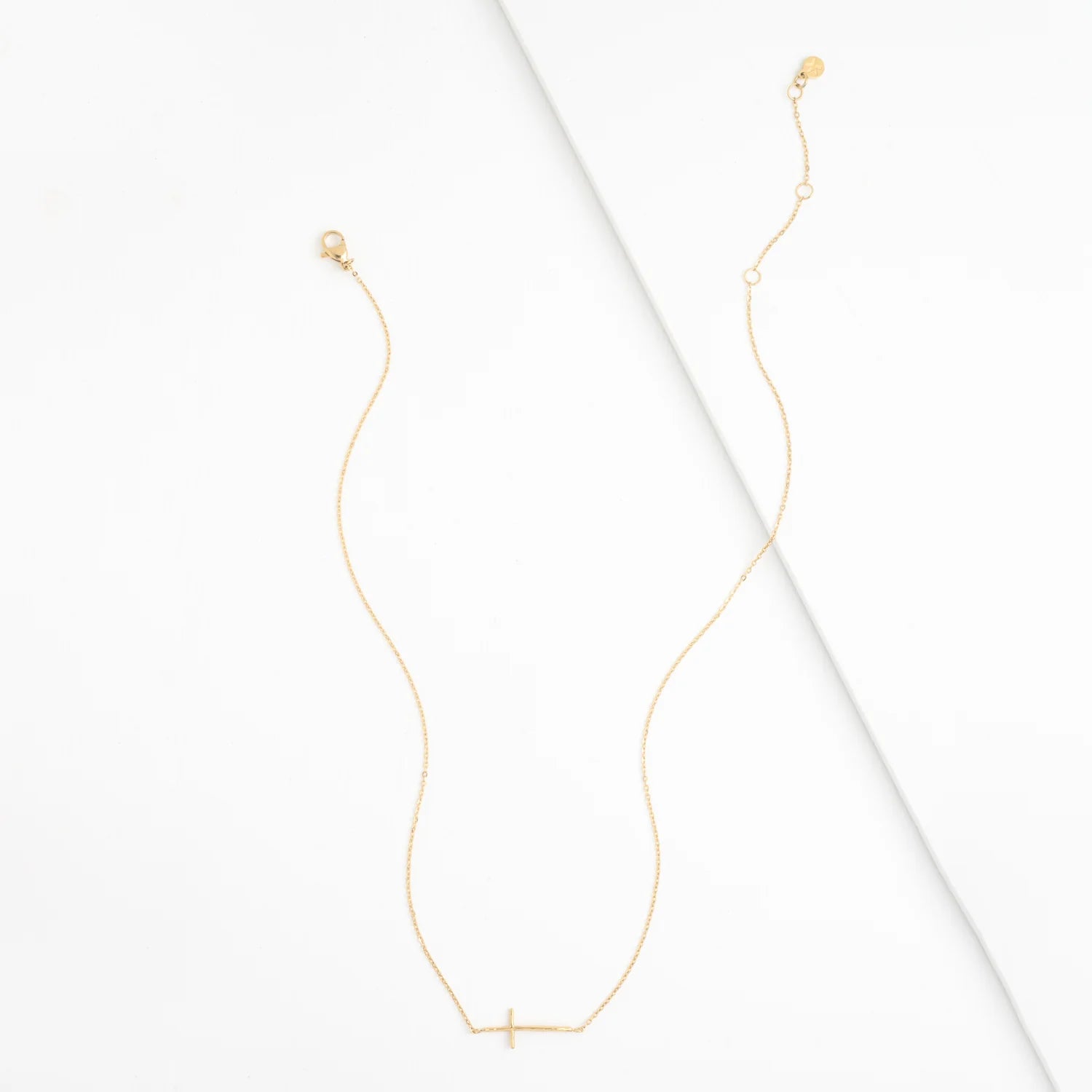 Gold necklace with a small cross pendant on a white background
