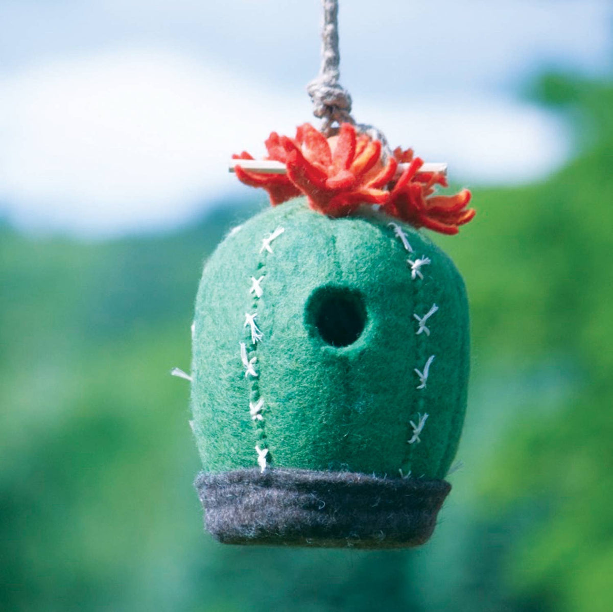 Felt cactus birdhouse with a red flower on a blurred green background