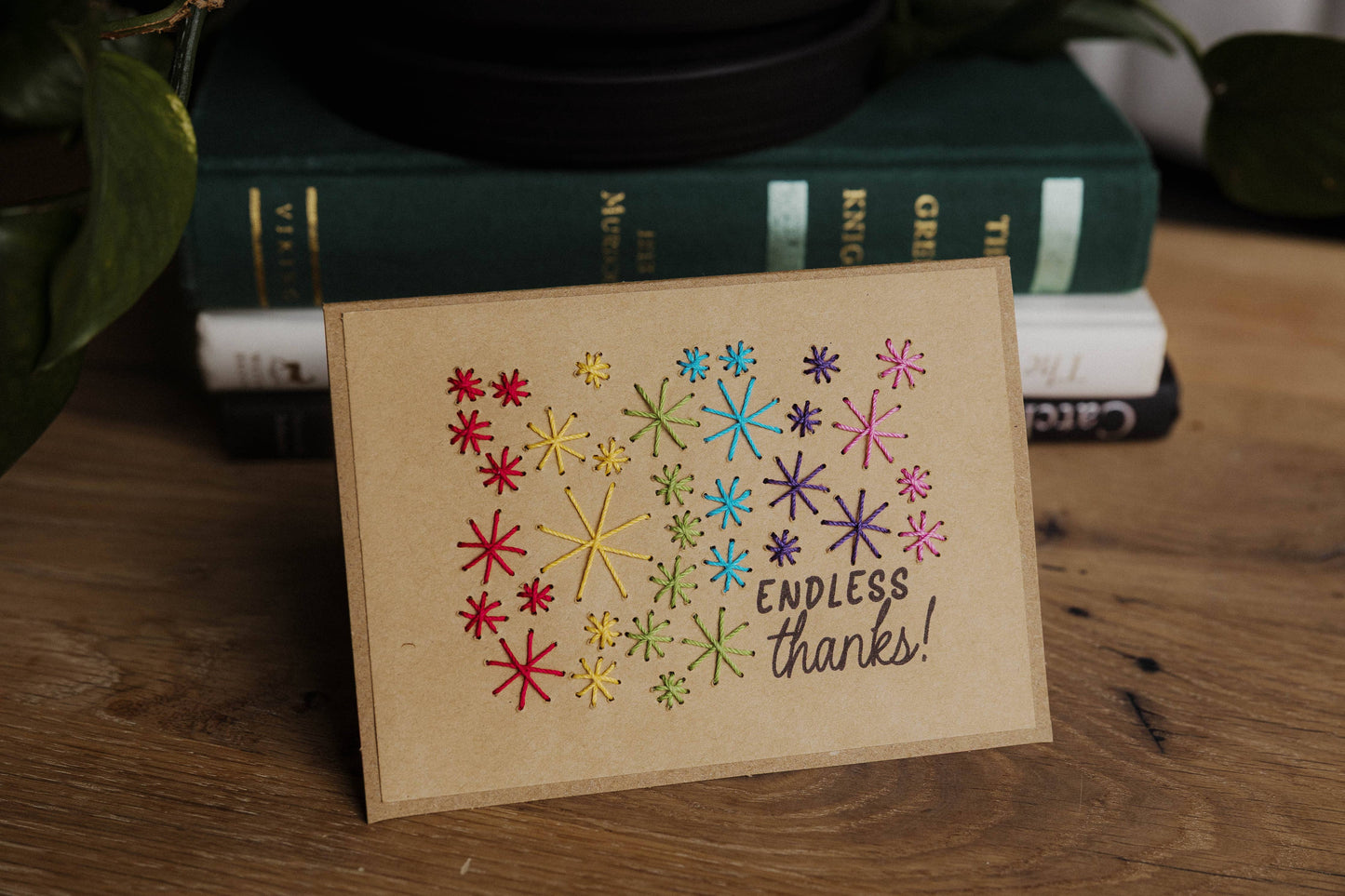 Card with colorful star patterns and 'Endless thanks!' text styled on a wooden surface with books in the background.