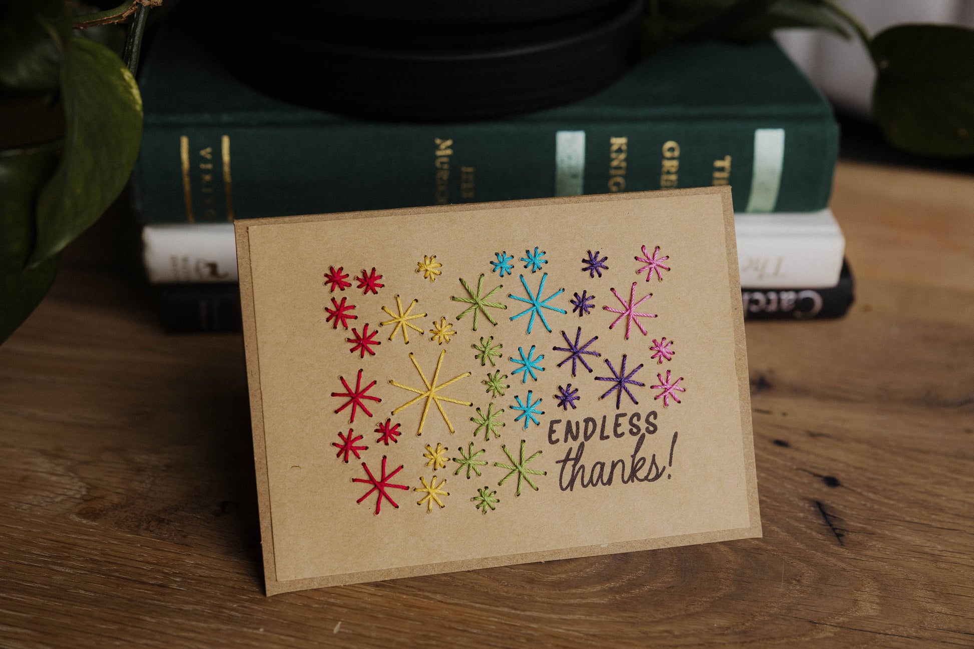 Card with colorful star patterns and 'Endless thanks!' text styled on a wooden surface with books in the background.