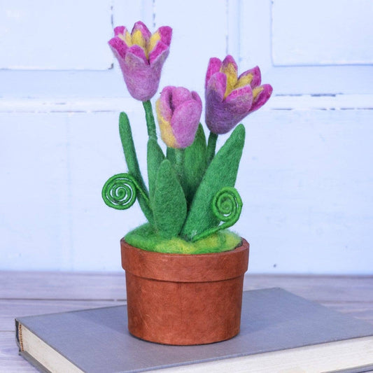 Felted pink and yellow tulip plant in a pot on a grey book with a light blue background