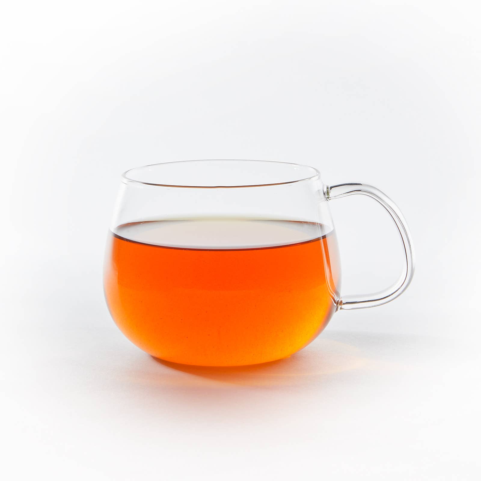 Clear glass mug filled with orange liquid on a white background