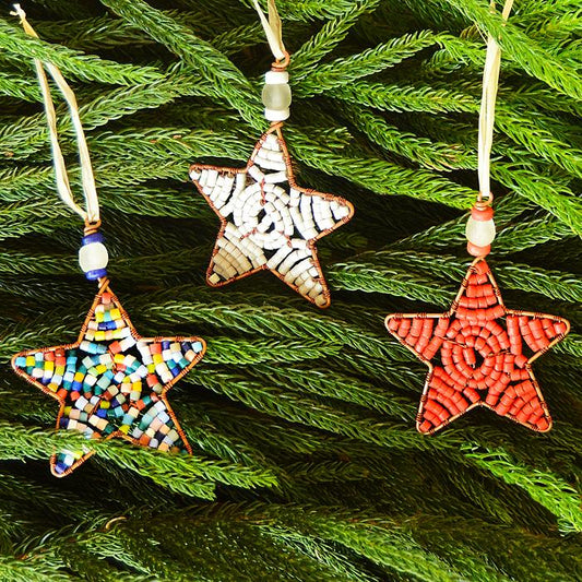 A collection of three glass beaded star ornaments on a tree.