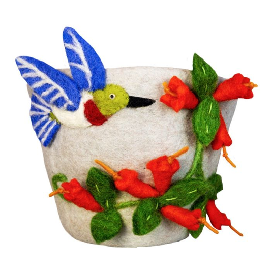 A handcrafted felted wool decorative plant pot cover featuring a blue and green hummingbird perched on a white pot, decorated with red Honeysuckle flowers and green leaves.