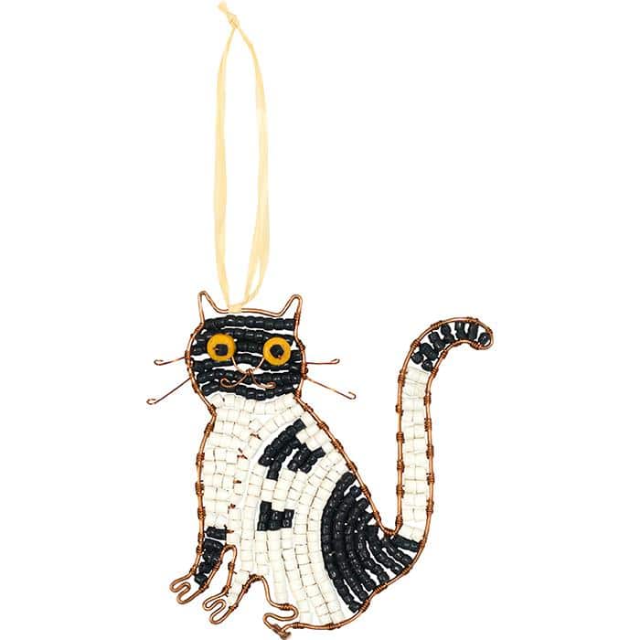 A tuxedo cat shaped glass bead ornament hanging on a piece of raffia.