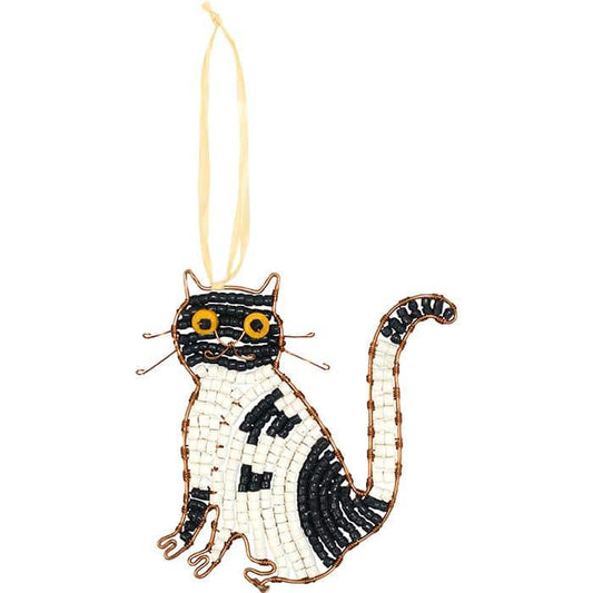 A tuxedo cat shaped glass bead ornament hanging on a piece of raffia.
