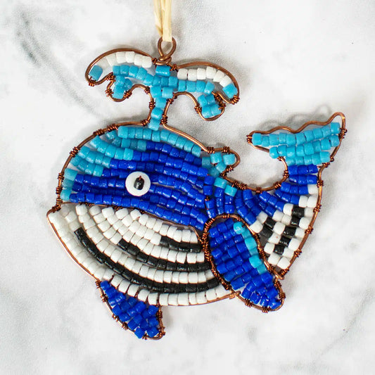 Blue and White whale shaped ornament made from glass beads and wired sits on a marble table.