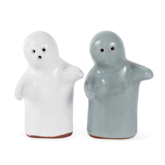 Two ceramic ghost-shaped salt and pepper shakers on a plain white background. One ghost is glossy white with a small brown base, and the other is matte light blue-gray with a small brown base.